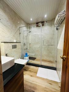 a bathroom with a shower with a glass door at Aruna Farm House in Kakarmatha
