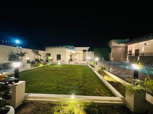 a backyard at night with a green lawn at Aruna Farm House in Kakarmatha