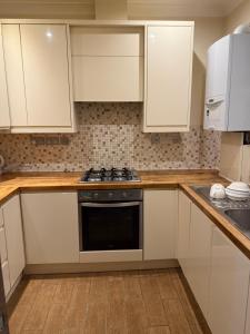 Una cocina con gabinetes blancos y un horno de estufa. en Bel Place, en Norwood