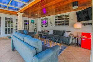 Una sala de estar con dos sofás azules y un televisor. en Vista Azul Lake Front Home with Hot Tub and Swim Spa, Fishing Dock, Gym, Game Room with Darts, Ping Pong, A Pool Table and more!, en Miami Lakes