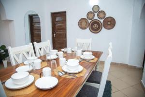 un tavolo in legno con piatti e piatti bianchi di Ndoto apartment a Ukunda
