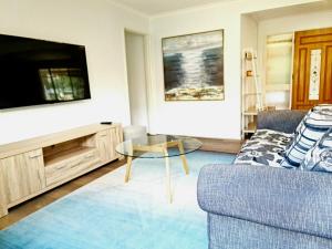 a living room with a couch and a tv at Close to beach and Mangrove walk in Batemans Bay