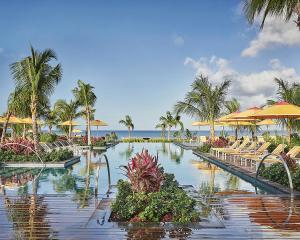 a resort with a pool with chairs and umbrellas at Four Seasons Resort Nevis in Nevis