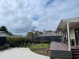 une maison avec une terrasse couverte et une allée. dans l'établissement Serenity Cottage Wonthaggi, à North Wonthaggi