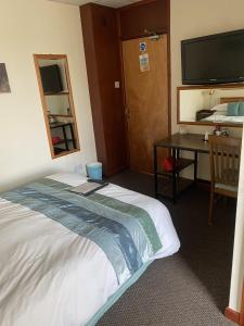 Un dormitorio con cama, escritorio y televisión. en Evanescent- Adult Only, en Blackpool