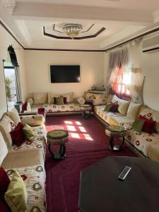 a living room with couches and a flat screen tv at Your new comfortable home with us in Laayoune