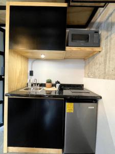 a kitchen with a black refrigerator and a microwave at Living Universidad in El Gallinero
