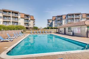 a swimming pool with chairs and a building at Steps to Sand! Condo with 2 Pools in Atlantic Beach in Atlantic Beach