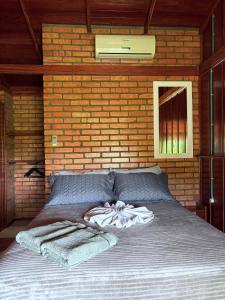 a bedroom with a bed with a brick wall at Pousada Porto Belo in Porto Belo