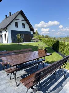 a picnic table and benches in front of a house at Agroturystyka Nad Lasem - Domki w górach in Toporzysko