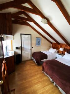 a attic room with two beds and a window at Hostal Dinamarca in Temuco