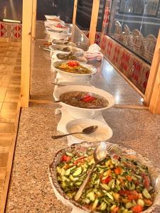 a buffet line of bowls of food on a counter at Layla Wadi Rum in Disah