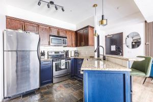a kitchen with blue cabinets and a stainless steel refrigerator at Westwinds - Funky Basecamp in the Rockies in Canmore