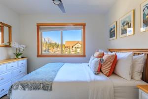 a bedroom with a bed and a window at Bluebird - Spacious Luxury Shared Rooftop Hot Tub in Canmore