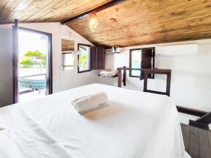 a bedroom with a white bed with a wooden ceiling at Casa do Mar Caraíva in Caraíva