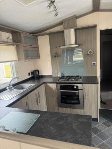 una cocina con estufa y fregadero en Spacious Modern Seaside Caravan, en Lossiemouth