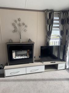 Una sala de estar con un televisor de pantalla plana en un centro de entretenimiento. en Spacious Modern Seaside Caravan, en Lossiemouth