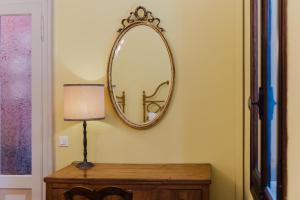 a mirror on a wall next to a table with a lamp at Antico Villino - Elegant Accommodation with Parking in Conegliano