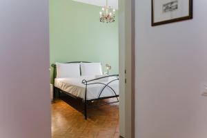 a bedroom with a bed with white sheets and a chandelier at Antico Villino - Elegant Accommodation with Parking in Conegliano