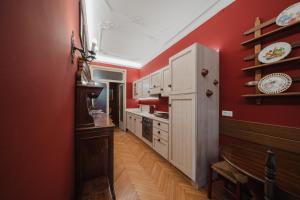 a kitchen with red walls and white cabinets at Antico Villino - Elegant Accommodation with Parking in Conegliano