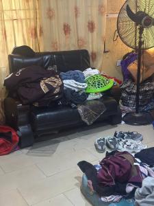 - un salon doté d'un canapé avec des vêtements et des chaussures dans l'établissement DarcoM, à Ile-Ife