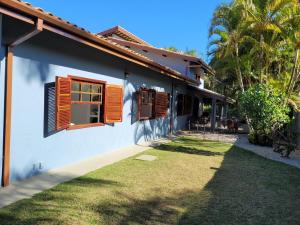 a white house with orange shuttered windows and a yard at Casa em Itamambuca com piscina em frente a praia in Ubatuba