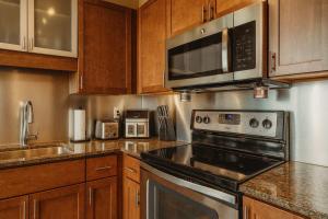 a kitchen with stainless steel appliances and wooden cabinets at Penthouse Loft Forest Park View Free Parking in Tower Grove +14 photos