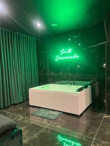 a bathroom with a tub and a neon sign at Suite Emeraude in Saint-Étienne