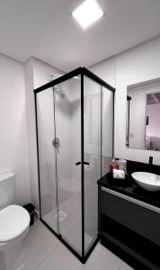 a bathroom with a shower and a toilet and a sink at Loft Blumenau in Blumenau
