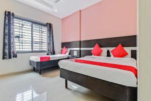 a bedroom with two beds and a window at Hotel O Sai Kohinoor in Shirdi