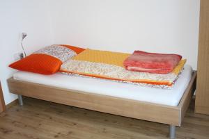 Una cama con mantas y almohadas coloridas. en Holzlehenhof, en Sankt Johann im Pongau