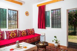 a living room with a red couch and windows at Paradise Farm 20 min from Rabat in Sale