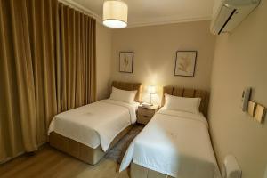 阿可贺巴Comfortable three-bedroom apartment in Olaya的一间卧室设有两张床、一个窗口和两盏灯。