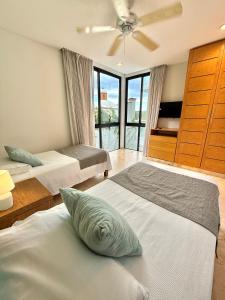 a bedroom with two beds and a ceiling fan at Anah Suites by Las Flores Vacation Rentals in Playa del Carmen