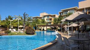 a resort swimming pool with chairs and tables and umbrellas at BEACH PARK PALM - COBERTURA Luxo in Aquiraz