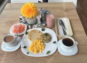a table with a plate of food and two cups of coffee at Aw Hotel Ariston Embassy in Bogotá