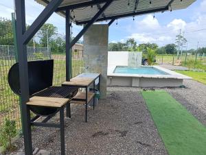 a pergola with a bench and a swimming pool at Maracuyá Garden Stanza 2 in Parrita