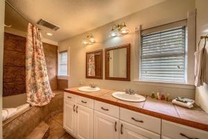 ein Badezimmer mit zwei Waschbecken und einer Badewanne und einem Spiegel in der Unterkunft Texas River Haus LD 1683 in New Braunfels