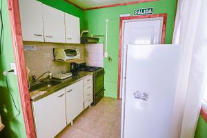 a kitchen with green walls and a white refrigerator at Cabaña familiar cerca del mar en Caleta Olivia in Caleta Olivia