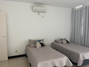 two beds in a room with white walls at Apartamento Mirante de Escarpas 1703 in Capitólio +23 photos