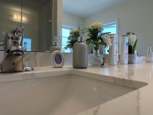 a bathroom counter with a sink with vases and flowers at Luxury 4BR Family Retreat in Thorold, Just 10 Mins from Niagara Falls, Clifton Hill & Wineries Free Wi-Fi, Free Parking in Thorold +92 photos