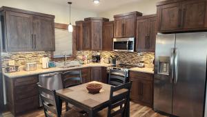 a kitchen with a table and a stainless steel refrigerator at Parkside Cabins in West Yellowstone