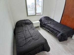 zwei schwarze Betten in einem Zimmer mit einem Spiegel in der Unterkunft depto moderno Calle Córdoba in San Miguel de Tucumán