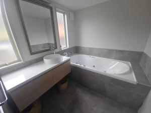 a bathroom with a tub and a sink and a mirror at The Bluffs Villa in Queenstown +20 photos