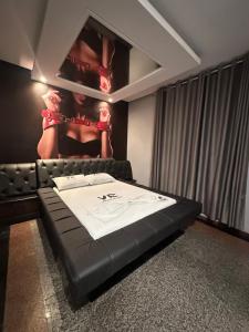 um quarto com uma cama com uma foto de uma mulher na parede em Motel Vitoria Reggia em São Vicente