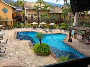 Una piscina en un resort con gente en ella. en Harmonia Flat Particular Ilhabela, en Ilhabela