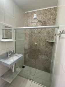 a bathroom with a glass shower with a sink at Pousada Japaratinga Good Vibes in Japaratinga