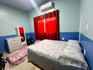 a bedroom with a bed and a red curtain at Suíte completa em Parintins in Parintins