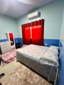 a bedroom with a bed with a red curtain at Suíte completa em Parintins in Parintins
