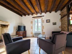 a living room with two chairs and a tv at Maison de vacances en Brenne avec piscine partagée, grand jardin et tout confort inclus - FR-1-591-329 in Bélâbre